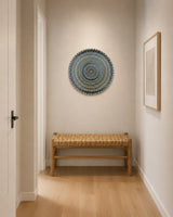 Buddy Light Forever round dot mandala wall art displayed above a woven bench in a bright hallway by Sweet Lilly Loves