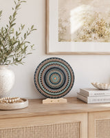 Copper Jewel original round dot mandala artwork displayed on a stand on a light console with framed wall art behind by Sweet Lilly Loves