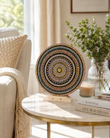 Crown of Echoes original round mandala artwork displayed on a small side table in a bright neutral room by Sweet Lilly Loves