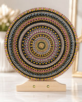 Crown of Echoes round dot mandala artwork displayed on a wooden stand in a light neutral interior by Sweet Lilly Loves