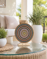 Crown of Echoes original copper, pink, gold and teal dot mandala artwork displayed on a timber stand on a glass table by Sweet Lilly Loves