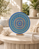 Divine Tide of Gold hand-painted dot mandala artwork displayed on a stand on a small round table by Sweet Lilly Loves