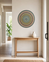 Golden Orange Orb hand-painted round mandala artwork displayed above a timber console in a bright entryway