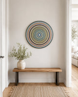 Golden Orange Orb original dot mandala wall art displayed above a simple wooden bench by Sweet Lilly Loves