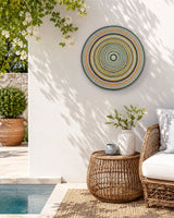 Golden Orange Orb round dot mandala wall art displayed in a bright outdoor seating space by Sweet Lilly Loves